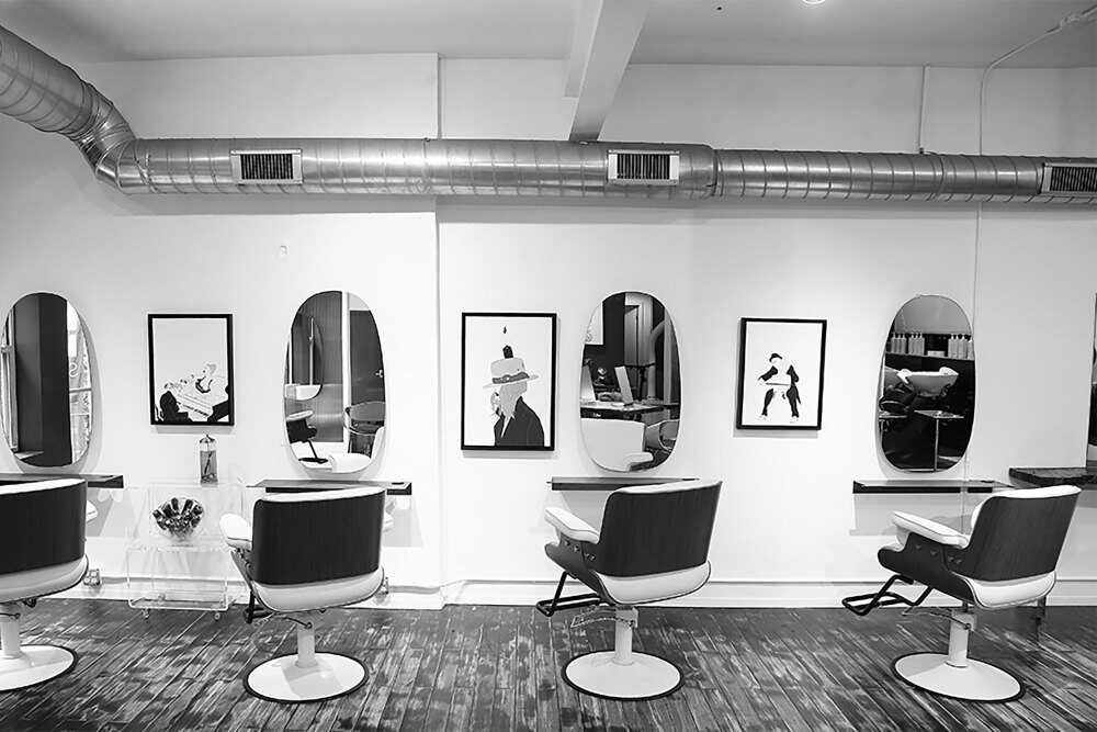 A line of styling stations with black chairs at Red Market New York
